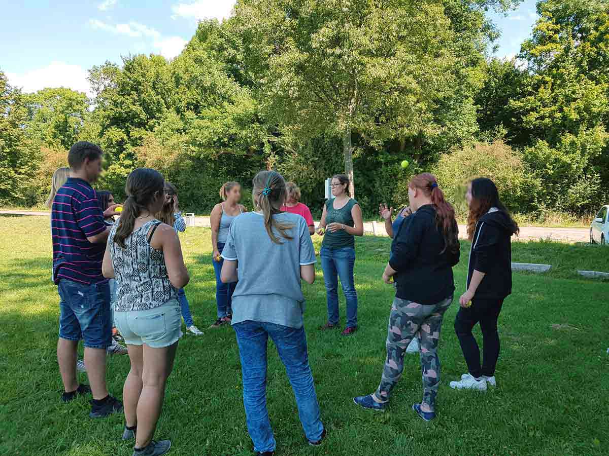 Junge Psychologin leitet eine Übung im Freien mit einer Gruppe Jugendlicher – Gruppen leiten ohne Angst durch praktische Anleitung.