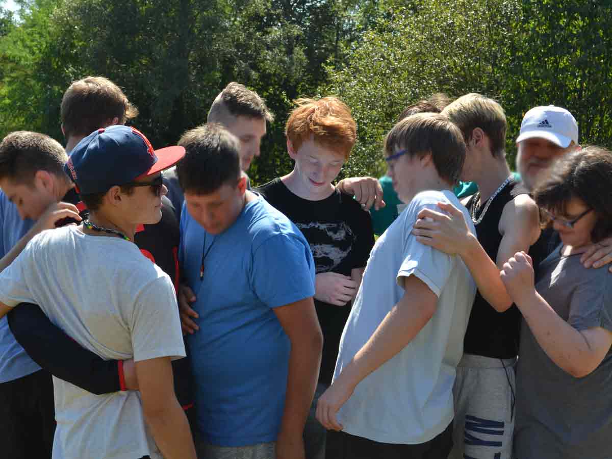 Gruppe von Auszubildenden in fröhlicher Stimmung bei einer Teamübung im Freien – lebendige Gruppenarbeit durch kreative Methoden.