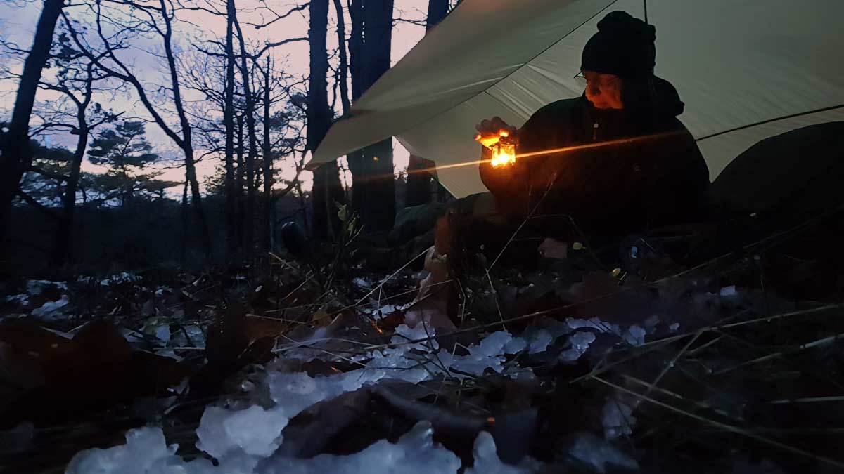 Mentor Götz Uwe Kreß nachts im verschneiten Winterwald mit kleiner Laterne. Übergang vom Licht in die heilsame Dunkelheit der Raunächte für Hochsensible.