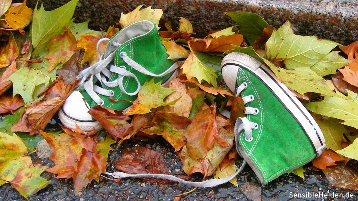 Grüne Kinderschuhe im Herbstlaub